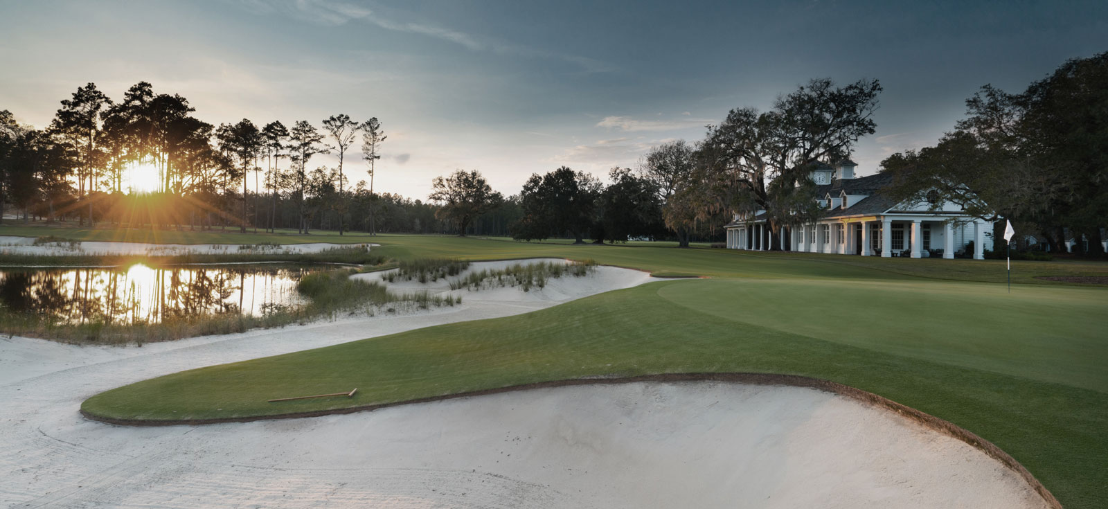 Photograph of a sunrise at the Congaree golf course from a sand trap looking onto the clubhouse